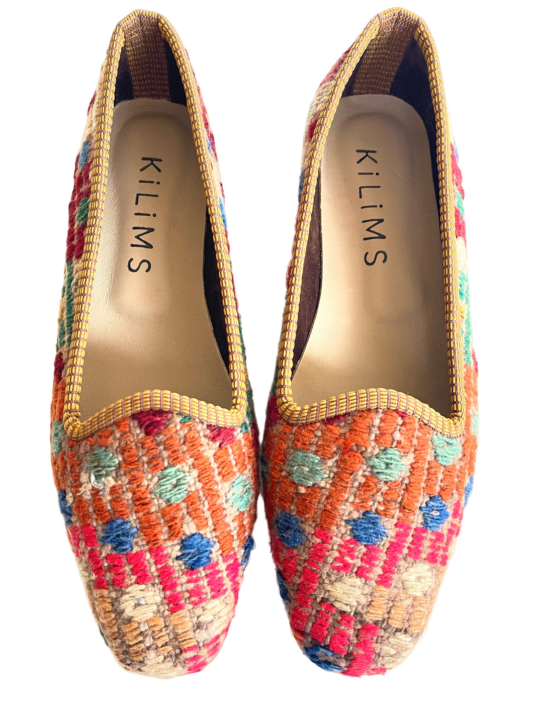 Colorful woven shoes with 'Kilims' branding on a white background