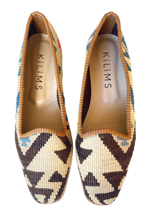 Pair of patterned slippers with 'Kilims' branding on a white background