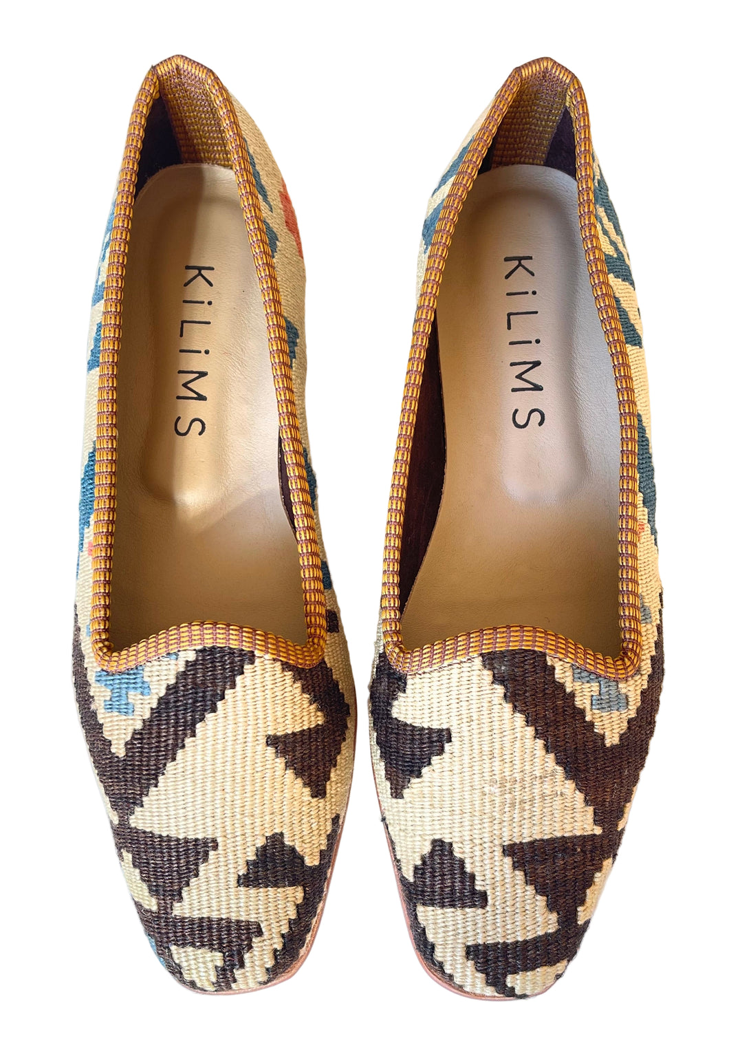 Pair of patterned slippers with 'Kilims' branding on a white background