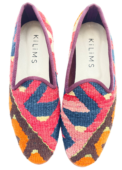 A pair of men's kilim slippers with a multicolored geometric pattern.